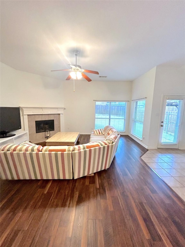 living room featuring a tiled fireplace, hardwood / wood-style floors, and ceiling fan