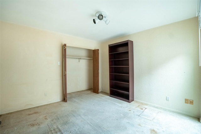 unfurnished bedroom featuring light colored carpet and a closet