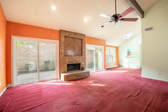 unfurnished living room featuring a brick fireplace, a wealth of natural light, a textured ceiling, and carpet