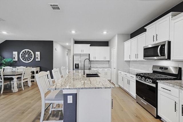 kitchen with an island with sink, stainless steel appliances, sink, and white cabinets