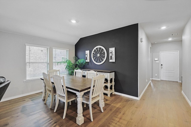 dining space with vaulted ceiling and light hardwood / wood-style floors