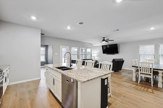 kitchen with sink, a center island with sink, appliances with stainless steel finishes, light stone countertops, and white cabinets