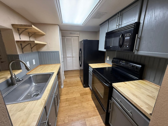 kitchen featuring sink, wood counters, and black appliances