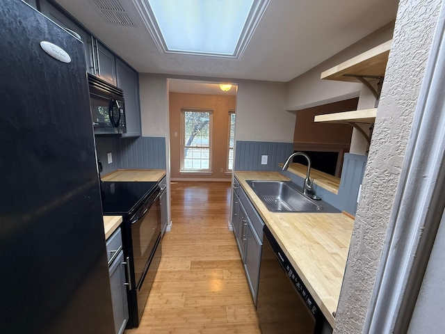 kitchen featuring sink, light wood-type flooring, and black appliances