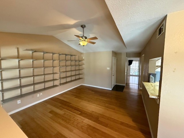 unfurnished living room featuring ceiling fan, lofted ceiling, a textured ceiling, and dark hardwood / wood-style flooring