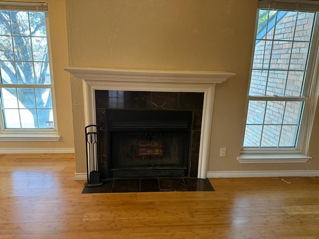 interior details with wood-type flooring and a tile fireplace