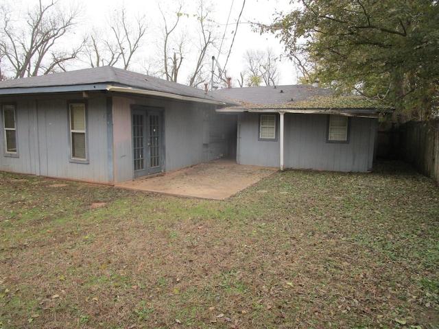 rear view of property featuring french doors, a patio area, and a lawn