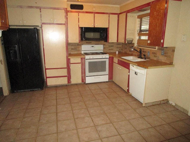 kitchen featuring sink, light tile patterned floors, crown molding, tasteful backsplash, and black appliances