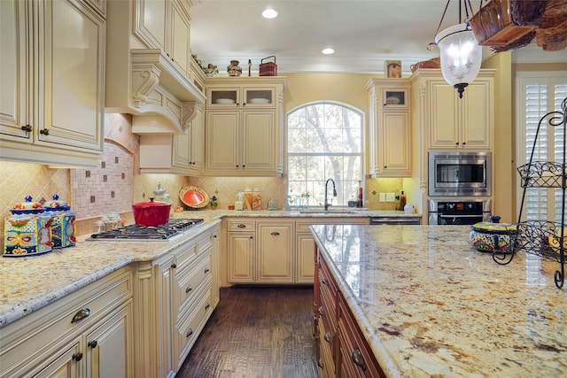 kitchen featuring sink, hanging light fixtures, appliances with stainless steel finishes, light stone countertops, and decorative backsplash