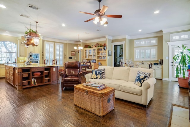 living room with ornamental molding, sink, dark wood-type flooring, and ceiling fan with notable chandelier