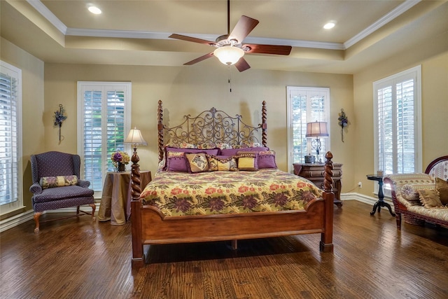 bedroom featuring a tray ceiling, dark wood-type flooring, ornamental molding, and ceiling fan