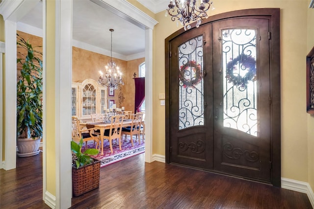 foyer entrance with french doors, dark hardwood / wood-style flooring, a chandelier, and crown molding