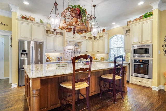 kitchen featuring a spacious island, appliances with stainless steel finishes, decorative light fixtures, and cream cabinets