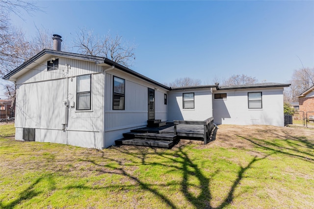 back of house with fence, a lawn, and a wooden deck