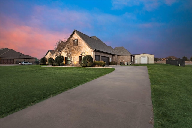 french country home featuring a garage and a lawn