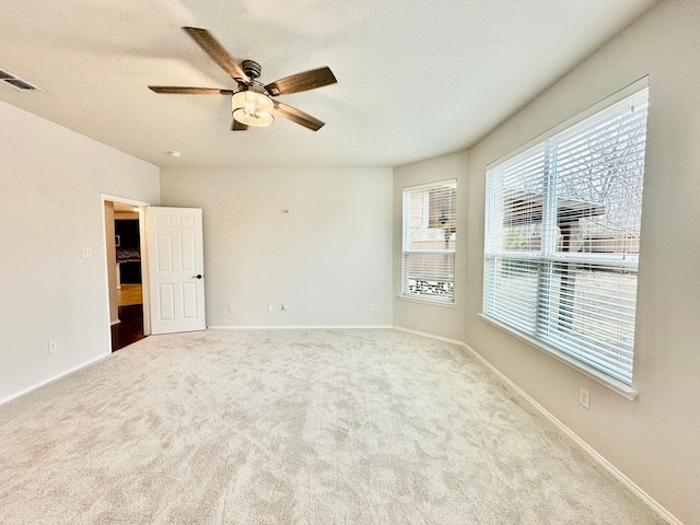 spare room featuring light carpet, ceiling fan, and a textured ceiling