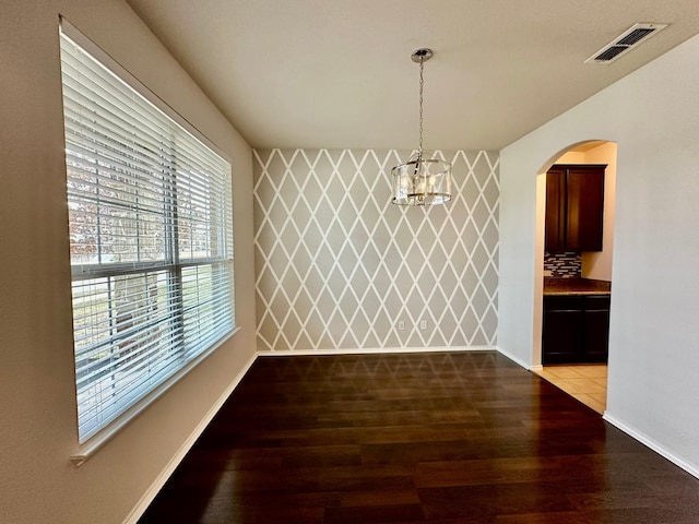 unfurnished dining area with an inviting chandelier and light wood-type flooring