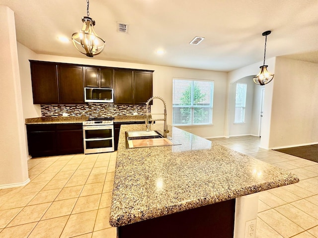 kitchen featuring light tile patterned flooring, sink, decorative light fixtures, dark brown cabinets, and range with two ovens