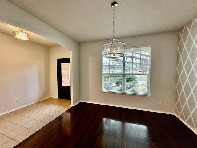 unfurnished dining area featuring a notable chandelier and light wood-type flooring