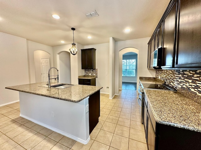 kitchen featuring pendant lighting, sink, appliances with stainless steel finishes, and a center island with sink