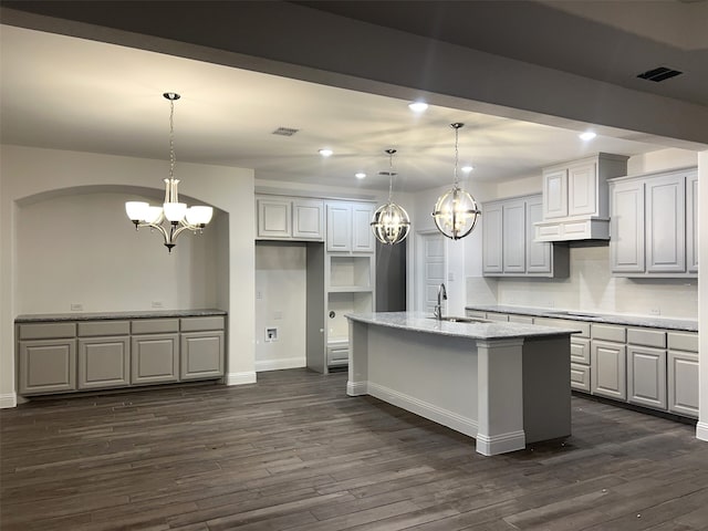 kitchen featuring a center island with sink, visible vents, a sink, and decorative light fixtures