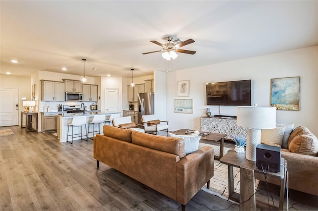 living room with light wood-style floors, ceiling fan, and recessed lighting