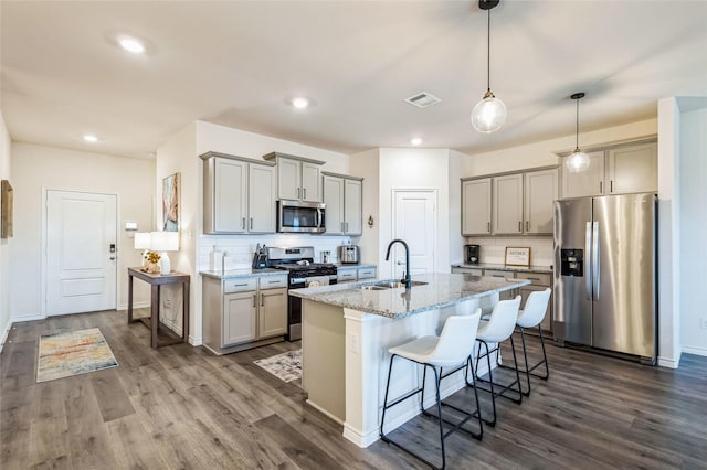 kitchen with appliances with stainless steel finishes, a kitchen bar, a sink, and gray cabinetry