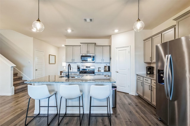 kitchen featuring appliances with stainless steel finishes, a breakfast bar, a sink, and gray cabinetry