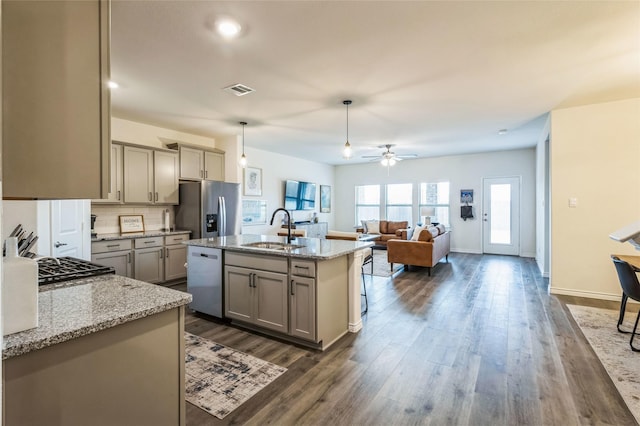 kitchen with backsplash, gray cabinetry, appliances with stainless steel finishes, dark wood-type flooring, and a sink