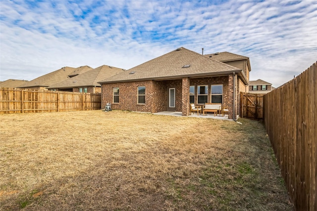 back of property with a patio area, a fenced backyard, a yard, and brick siding