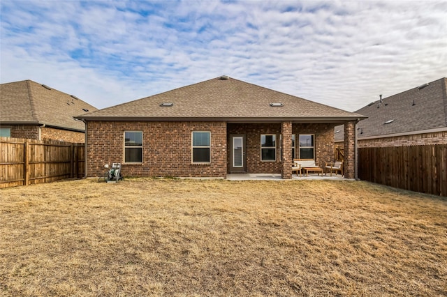 rear view of property with a patio area, brick siding, and a fenced backyard