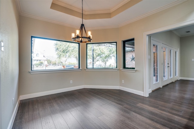 empty room featuring plenty of natural light, dark wood-type flooring, a notable chandelier, and a tray ceiling