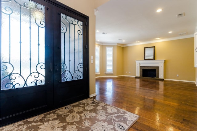 foyer with a fireplace, ornamental molding, french doors, and wood-type flooring