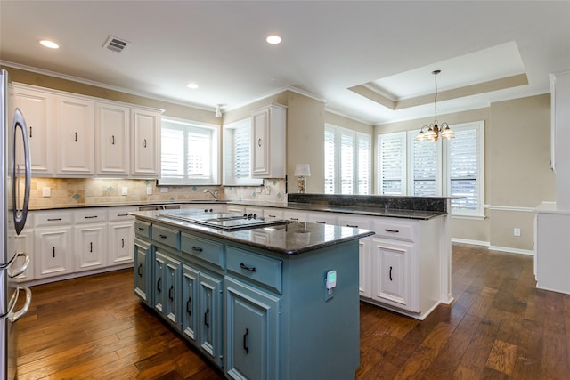 kitchen featuring blue cabinets, white cabinetry, a center island, stainless steel fridge, and dark stone counters