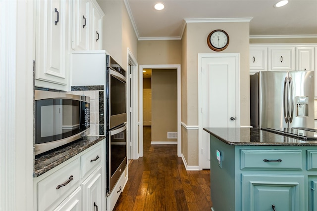 kitchen featuring crown molding, appliances with stainless steel finishes, dark stone countertops, dark hardwood / wood-style floors, and white cabinets