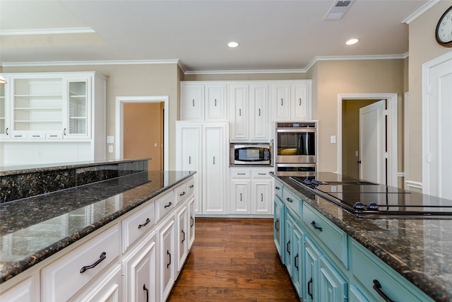 kitchen with appliances with stainless steel finishes, white cabinets, dark hardwood / wood-style flooring, dark stone counters, and blue cabinetry