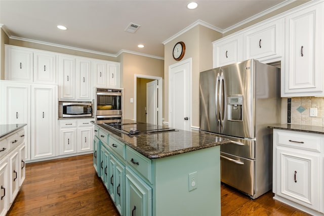 kitchen featuring appliances with stainless steel finishes, white cabinets, a kitchen island, green cabinetry, and dark stone counters