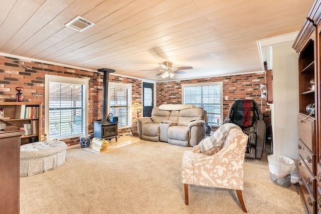 carpeted living room with brick wall, a wood stove, wood ceiling, and plenty of natural light