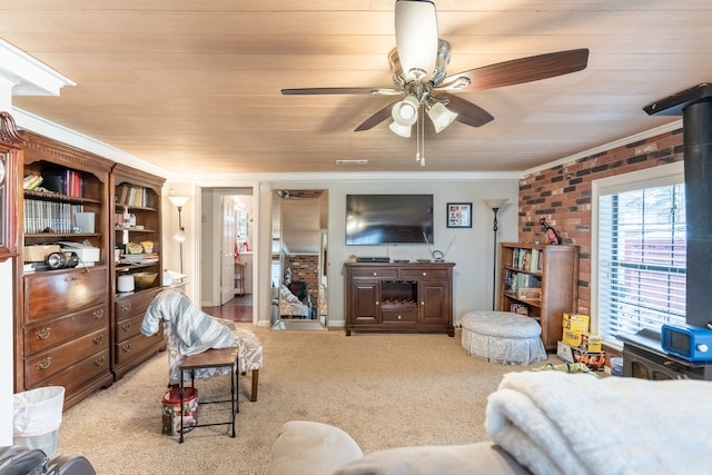 living room featuring crown molding, a wood stove, light colored carpet, and ceiling fan