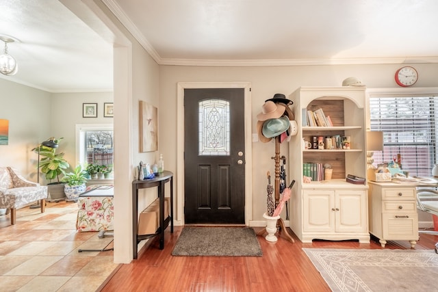 entryway with ornamental molding and light hardwood / wood-style floors