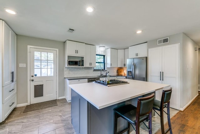 kitchen with white cabinetry, appliances with stainless steel finishes, a kitchen bar, and a center island