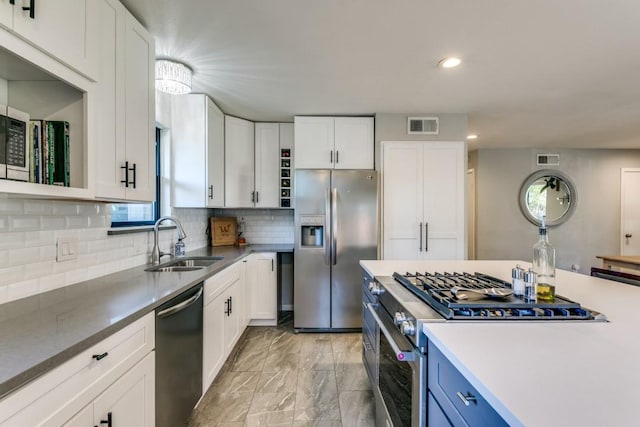 kitchen featuring blue cabinetry, sink, tasteful backsplash, appliances with stainless steel finishes, and white cabinets