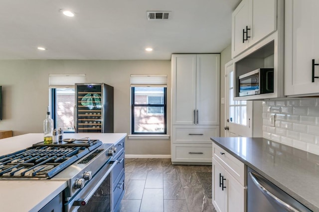 kitchen with white cabinetry, appliances with stainless steel finishes, decorative backsplash, and wine cooler