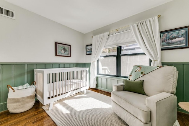 bedroom with a crib and dark hardwood / wood-style floors