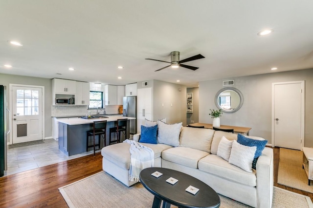 living room featuring ceiling fan, a healthy amount of sunlight, and light wood-type flooring