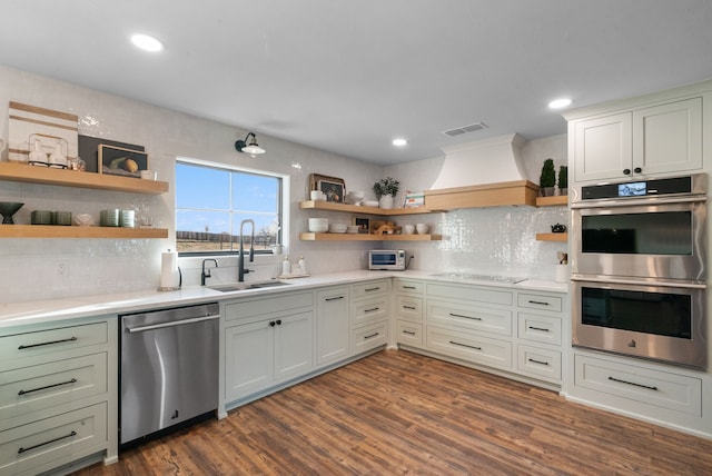 kitchen with premium range hood, appliances with stainless steel finishes, sink, and dark hardwood / wood-style flooring