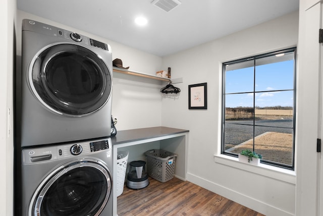 laundry area with dark wood-type flooring and stacked washer and clothes dryer