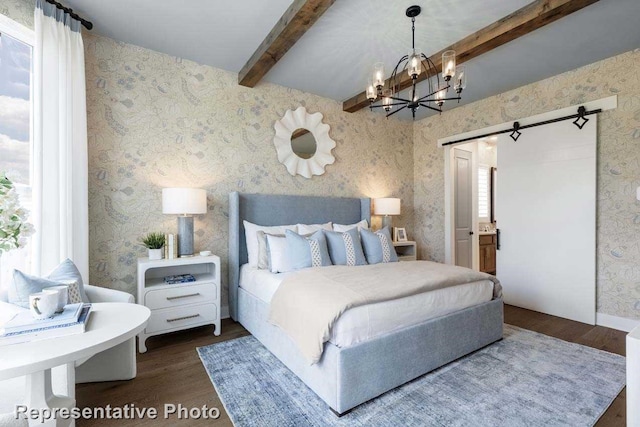 bedroom with ensuite bathroom, a notable chandelier, a barn door, dark wood-type flooring, and beam ceiling