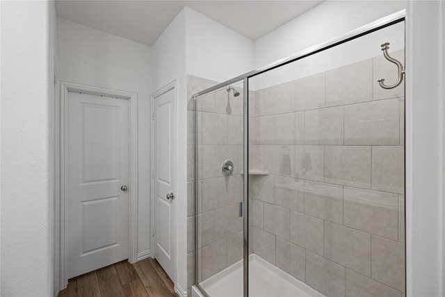 bathroom with hardwood / wood-style floors and a shower with shower door