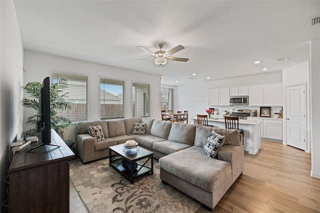 living room featuring ceiling fan and light hardwood / wood-style flooring